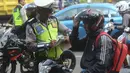 Polantas membuat surat tilang untuk pengendara motor ketika Operasi Patuh Jaya 2018 di ruas Jalan DI Panjaitan, Jakarta Timur, Jumat (27/4). Oparasi tersebut digelar untuk meningkatkan ketertiban dan kepatuhan berlalu lintas. (Merdeka.com/Imam Buhori)