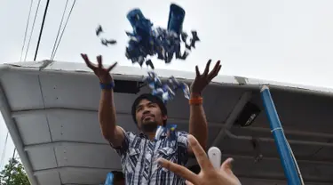  Mantan petinju Filipina, Manny Pacquiao melempar baju dan permen untuk pendukung selama kampanye di kota Calamba, Provinsi Laguna, selatan Manila (28/4). Manny Pacquiao akan ikut  pemilihan menjadi senat Filipina. (AFP PHOTO/TED aljibe)