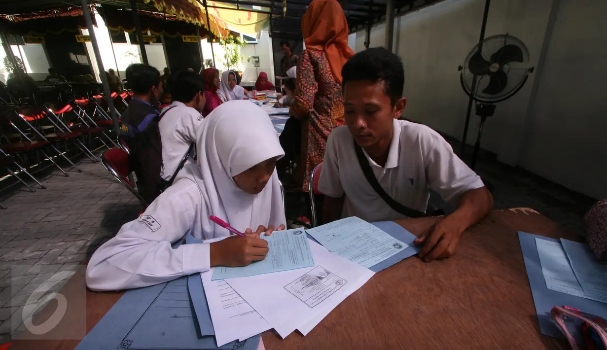 Siswi didampingi orangtuanya mengisi formulir Penerimaan Peserta Didik Baru (PPDB) di Dinas Pendidikan Kota Yogyakarta, Rabu (15/6). PPDB jalur pemegang Kartu Menuju Sehat (KMS) diminati siswa untuk mendapatkan sekolah favorit. (Liputan6.com/Boy Harjanto)