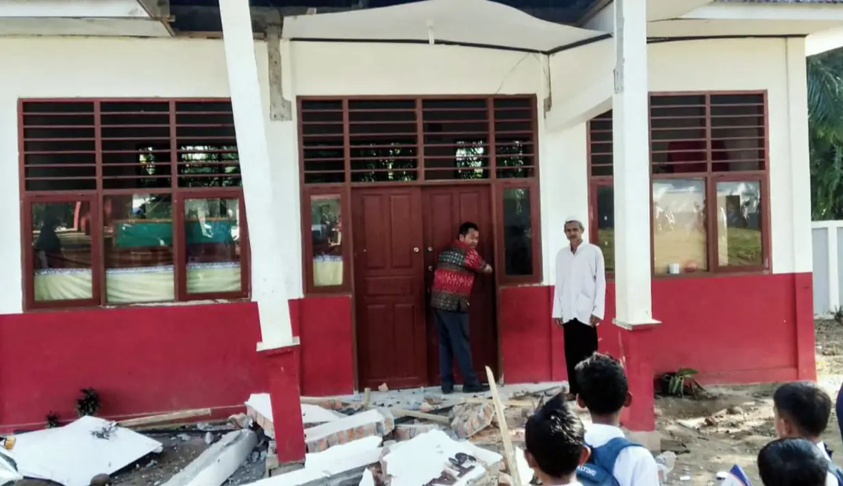Warga memeriksa bangunan yang rusak akibat gempa Magnitudo 6,2 di Desa Kajai, Pasaman Barat, Sumatera Barat, Jumat (25/2/2022). Sejumlah bangunan rusak akibat guncangan gempa. (SULTHAN AZZAM/AFP)