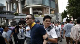 Salah satu anggota kelompok anti-demokrasi diamankan petugas kepolisian setempat dari lokasi utama berlangsungnya aksi demonstasi massa pro-demokrasi di Admiralty, Hong Kong, (13/10/2014). (REUTERS/Carlos Barria)