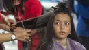 Seorang wanita mengikuti cukur rambut gratis saat acara amal di Surabaya, Jawa Timur, Senin (8/11/2021). Layanan cukur rambut gratis ini dilakukan kepada 100 anak yatim piatu. (Juni Kriswanto/AFP)