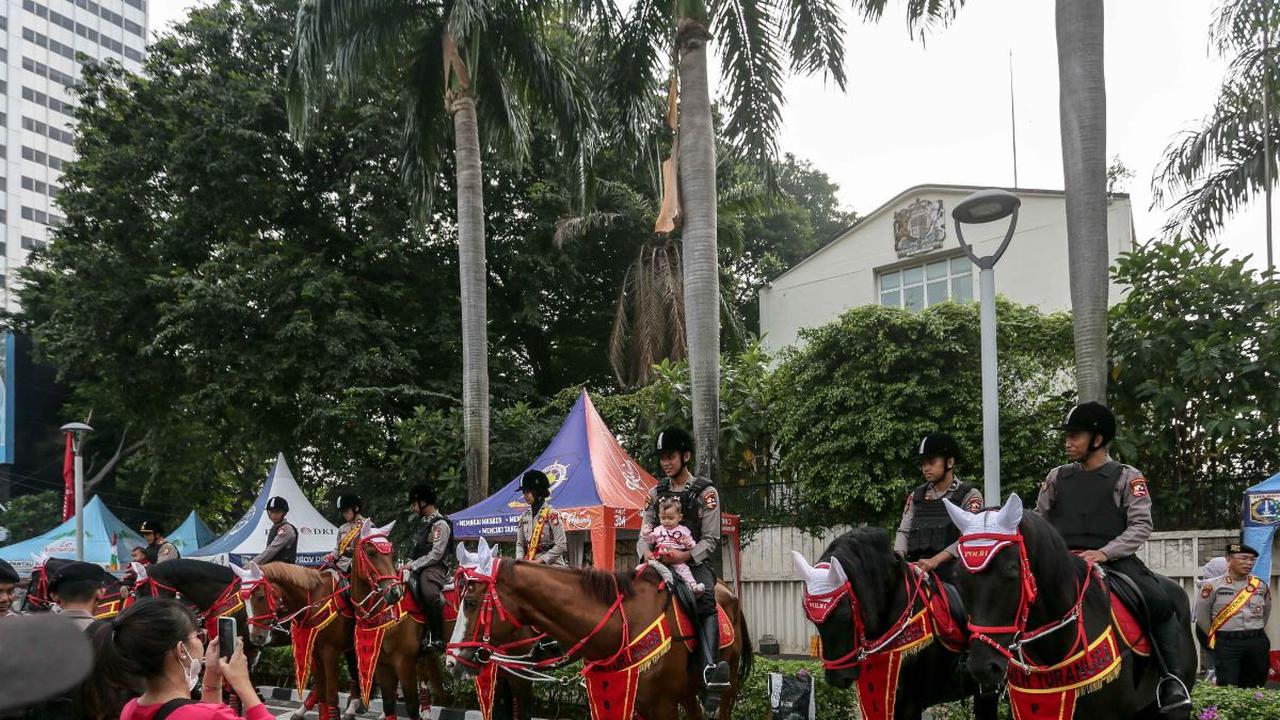 Sejumlah warga dan anak-anak berfoto dengan Polisi Berkuda dari Detasemen Turangga Direktorat Polisi Satwa Polri saat Hari Bebas Kendaraan Bermotor di kawasan Bundaran HI, Jakarta, Minggu (13/8/2023).