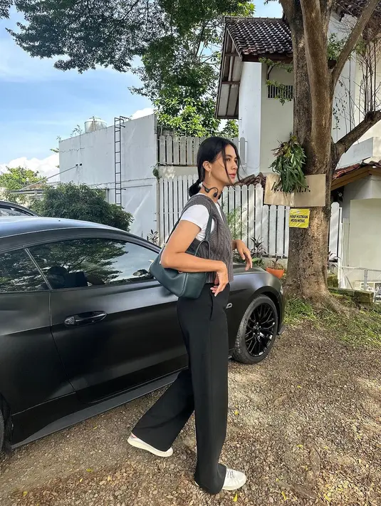 Ia memadukan white t-shirt dengan knit vest dan loose pants. Penampilannya dilengkapi dengan sneakers dan sling bag. [@paula_verhoeven]