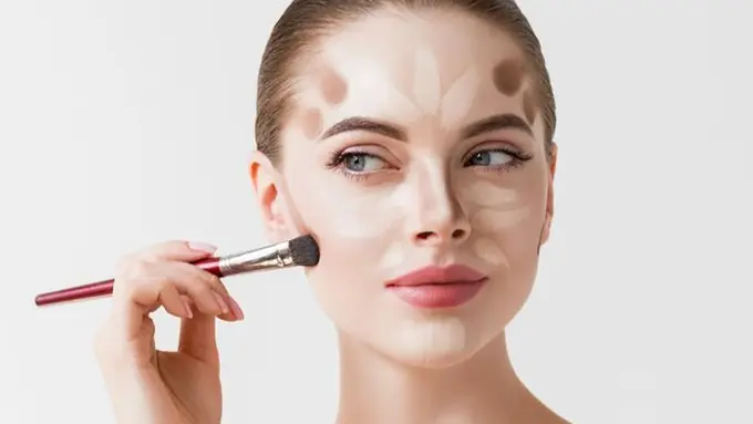 Seorang perempuan sedang mengaplikasikan contour di wajahnya menggunakan brush make up (Foto Dok: Freepik/kiraliffe)