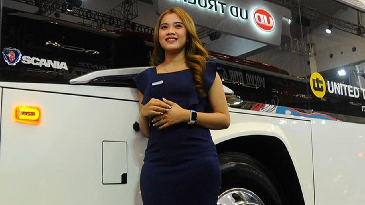 Seorang SPG berdiri di sebelah bus untuk memandu para pengunjung.