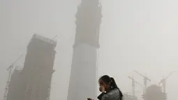 Seorang wanita menutup mulutnya dengan tangan saat badai debu menerjang kota Beijing, China, Kamis (4/5). Badai debu itu menyelimuti bangunan dan permukiman di Beijing. (AP Photo/Andy Wong)