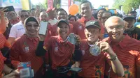 Menteri BUMN RI Rini M Soemarno (tengah) menunjukkan aplikasi pembayaran digital LinkAja yang digunakan oleh para finisher untuk mendapatkan medali BNI ITB Ultra Maraton 2019 di Kampus ITB, Bandung, Minggu (13 Oktober 2019).