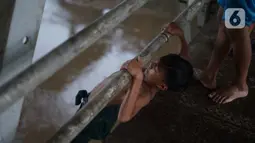 Anak-anak melompat dari jembatan ke Sungai Ciliwung, Rawajati, Jakarta, Selasa (17/12/2019). Meski debit air Sungai Ciliwung naik akibat hujan mengguyur Jakarta sejak siang hingga sore, anak-anak tersebut tetap nekat berenang tanpa memedulikan keselamatan. (Liputan6.com/Immanuel Antonius)