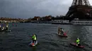 Peserta menyeberangi sungai Seine dekat menara Eiffel selama Nautic Paddle Race di Paris, Minggu (9/12). Sekitar 800 orang mengikuti lomba dayung sambil berdiri terbesar di dunia sejauh 11 km dengan pemandangan kota Paris. (AP /Christophe Ena)