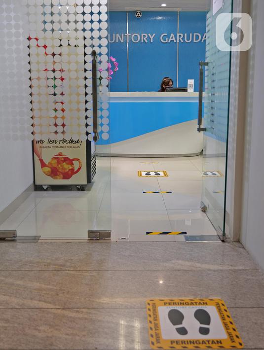Tanda jaga jarak yang dipasang di lantai kantor  Suntory Garuda, Jakarta, Senin (8/8/2020). Suntory Garuda menerapkan protokol kesehatan, seperti kapasitas karyawan hanya dibolehkan sebanyak 50 persen, meniadakan absensi sidik jari dan menggunakan alat makan pribadi. (Liputan6.com/Herman Zakharia)