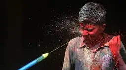 Seorang anak India terkena semprotan air berwarna selama festival Holi di Chennai (2/3). Holi, festival musim semi hindu di India yang diadakan 2 Maret tahun ini pada akhir musim dingin pada bulan purnama pertama kalender lunar. (AFP Photo/Arun Sankar)
