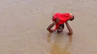 Pangi Satiabu terlihat tengah memegang bayinya sambil menerjang banjir
