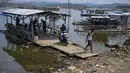Warga mengarahkan rakit penyeberangan ke tepi bendungan  yang menyusut di dekat Kampung Somang di Lebak, Banten, Kamis (30/7/2026). (AFP/ Bay Ismoyo)