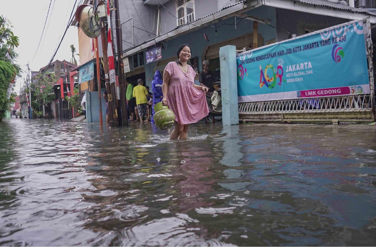 FOTO: Drainase Meluap, Warga Pasar Rebo Terobos Genangan