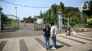 Sejumlah warga mengambil gambar dari depan kawasan Monumen Nasional (Monas), Jakarta, Minggu (26/7/2020). Sejumlah warga mulai mengunjungi kawasan Monas meski masih ditutup sementara di masa PSBB transisi. (Liputan6.com/Faizal Fanani)
