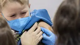 Seorang bocah berusia 5 tahun menerima suntikan dosis pertama vaksin corona COVID-19 di Wina, Austria, Senin (15/11/2021). Pihak berwenang mulai hari Senin memvaksinasi anak-anak berusia antara 5 dan 11 tahun di ibu kota. (JOE KLAMAR / AFP)