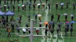 Warga mengantre untuk dites virus corona di pusat pengujian sementara meskipun hujan di Hong Kong, 22 Februari 2022. Hong Kong akan melakukan pengujian Covid-19 untuk seluruh penduduknya pada Maret mendatang, saat kota itu bergulat dengan wabah terburuk dari varian omicron. (AP Photo/Kin Cheung)