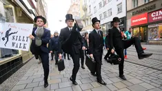 Sejumlah pria mengenakan kostum berjalan dengan mengangkat tinggi kakinya di Brno, Republik Ceko (7/1). Mereka berjalan dengan mengenakan kostum tersebut dalam acara International Silly Walk Day.  (AFP Photo/Radek Mica)