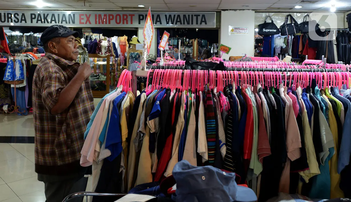 Pengunjung mencoba pakaian bekas impor yang dijajakan pedagang di Pasar Baru Metro Atom, Jakarta, Jumat (6/12/2019). Pakaian bekas impor yang dijual di kios-kios pasar masih banyak diminati lantaran harga yang ditawarkan sangat terjangkau. (merdeka.com/Imam Buhori)