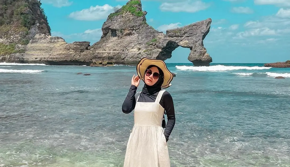 Mengenakan dres dan topi, menghadirkan kesan musim panas yang khas. Gaya sederhana yang diusung Putri Delina bisa jadi opsi seru untuk berlibur ke pantai. (Foto: Putri Delina/ Instagram)