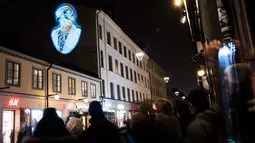Sejumlah warga memperhatikan karya Julien Nonnon yang ditampilkan di sebuah bangunan di Sodermalm, Stockholm, Swedia (25/11). Pameran seni ini menggunakan sebuah teknik untuk memproyeksikan gambar pada permukaan datar. (AFP/Jonathan Nackstrand)