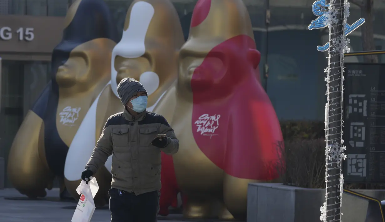 Seorang pria yang mengenakan masker berjalan di dekat dekorasi di sebuah pusat perbelanjaan di Beijing, China, Selasa (14/12/2021). Kasus pertama varian omicron COVID-19 telah terdeteksi di daratan negara di kota Tianjin di sebelah timur Beijing. (AP Photo/Ng Han Guan)