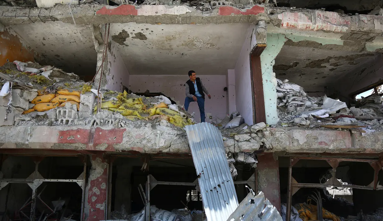 Warga melihat bangunan yang rusak dan hancur akibat bentrokan antara pasukan keamanan Turki dan gerilyawan Kurdi di Yuksekova, provinsi tenggara Hakkari , Turki , 30 Mei 2016. (REUTERS / Sertac kayar)
