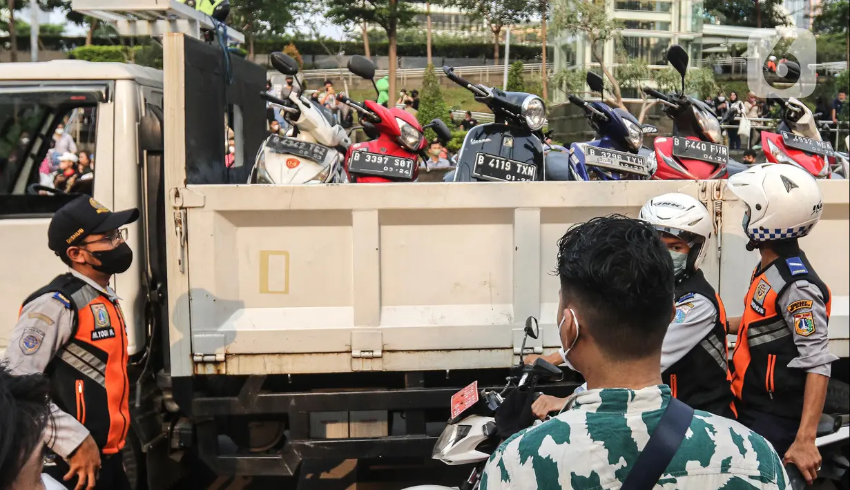 Sebuah truk mengangkut sejumlah motor yang terjaring razia parkir liar  di lokasi Citayam Fashion Week, kawasan Stasiun Dukuh Atas, Sudirman, Selasa (26/7/2022). Satpol PP dan Dinas Perhubungan (Dishub) DKI Jakarta mengamankan sebanyak 16 sepeda motor yang terpakir secara liar. (Liputan6.com/Faizal Fanani)