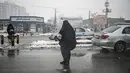 Seorang wanita mengenakan burqa memohon di sepanjang jalan saat hujan salju di Kabul (4/1/2022). Sedikitnya tujuh warga Afghanistan tewas dan 26 lainnya cedera dalam beberapa kecelakaan lalu lintas. (AFP/Mohd Rasfan)