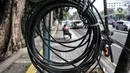 Warga duduk di bawah jaringan kabel utilitas yang menjuntai di Jalan Proklamasi, Pegangsaan, Kecamatan Menteng, Jakarta Pusat, Kamis (6/10/2022). Minimnya pengawasan dalam tahap penyelesaian proyek revitalisasi trotoar oleh pihak terkait menyebabkan jaringan kabel utilitas di kawasan tersebut semrawut  yang dapat membahayakan keselamatan pengguna jalan, terutama saat musim penghujan. (merdeka.com/Iqbal S. Nugroho)