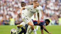 Pemain Barcelona Ansu Fati (kanan) berebut bola dengan pemain Real Madrid, Toni Kroos saat pertandingan sepak bola La Liga Spanyol di Stadion Santiago Bernabeu, Madrid, Minggu (16/10/2022). Pada pertandingan ini kedua tim saling berbalas serangan sejak awal permainan. Namun, usai 10 menit babak pertama Real Madrid tampil lebih menekan. (AP Photo/Manu Fernandez)