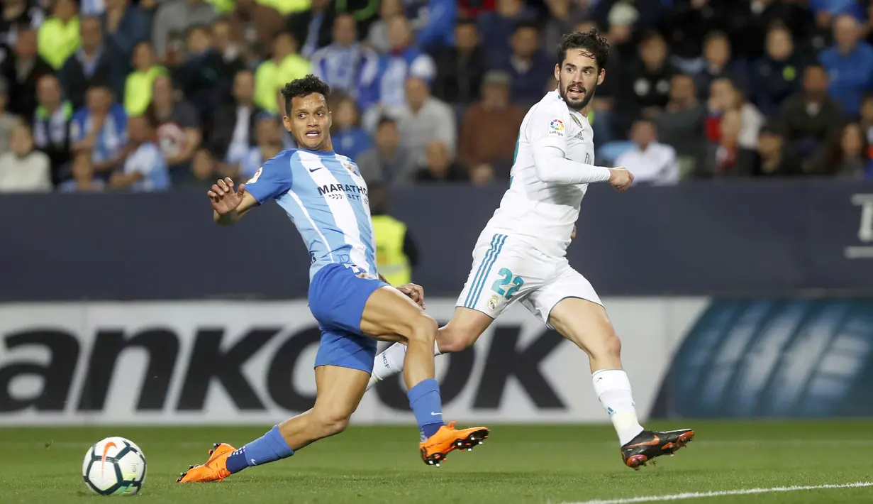 Pemain Real Madrid, Isco (kanan) melepaskan tembakan melewati adangan pemain Malaga, Roberto Jose Rosales pada lanjutan La Liga Santander di Rosaleda stadium, Malaga, (15/4/2018). Madrid menang 2-1. (AP/Miguel Morenatti)