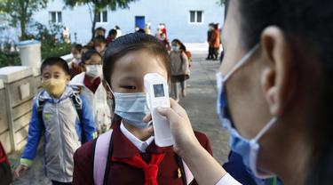 Seorang guru mengukur suhu tubuh seorang siswi untuk membantu mengekang penyebaran virus corona sebelum memasuki Sekolah Dasar Kim Song Ju di Distrik Pusat di Pyongyang, Korea Utara, Rabu, 13 Oktober 2021. (Foto AP/Cha Song Ho, File)