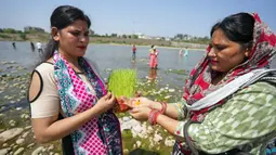 Umat Hindu bersiap untuk membenamkan bibit jelai sebagai persembahan saat Festival Navratri di Sungai Tawi, Jammu, India, 10 April 2022. Sesaji tersebut dibuat sebagai bagian dari ritual menandai berakhirnya festival selama sembilan hari. (AP Photo/Channi Anand)