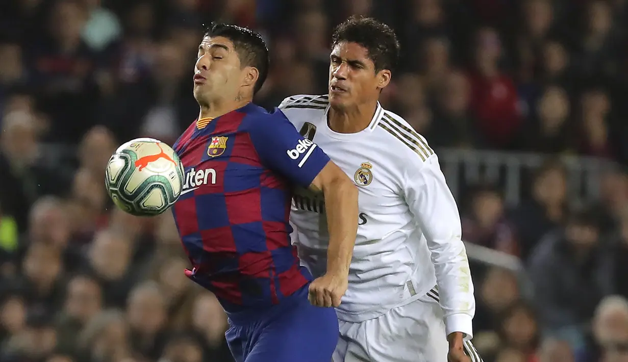 Penyerang Barcelona, Luis Suarez mengontrol bola dari kawalan bek Real Madrid, Raphael Varane pada pertandingan lanjutan La Liga Spanyol di stadion Camp Nou (18/12/2019). Barcelona bermain imbang 0-0 atas Real Madrid. (AP Photo/Emilio Morenatti)