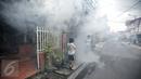 Seorang anak menutup hidungnya saat dilakukan pengasapan (Fogging) di kelurahan Menteng, Jakarta, Senin (8/2). Pengasapan dilakukan untuk mencegah wabah penyakit demam berdarah yang kerap muncul pada peralihan musim. (Liputan6.com/Faizal Fanani)