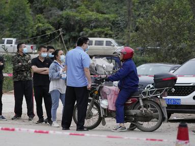 Petugas pemerintah mengontrol akses di pintu masuk desa Lu mengarah ke lokasi jatuhnya pesawat China Eastern di Guangxi, China barat daya, Selasa (23/3/2022). Kecelakaan pesawat dengan 132 orang di dalamnya itu memicu api yang cukup besar dan terlihat pada citra satelit NASA. (AP Photo/Ng Han Guan)