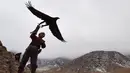 Seorang pemburu elang melepaskan burungnya, elang emas, saat festival berburu "Salburun" di desa Tuura-Suu, sekitar 280 km dari Bishkek, Kyrgyzstan, Selasa (23/2/2021). Salburun berasal dari tradisi nomaden berburu dan melindungi penggembala dari predator seperti serigala. (VYACHESLAV OSELEDKO/AFP)