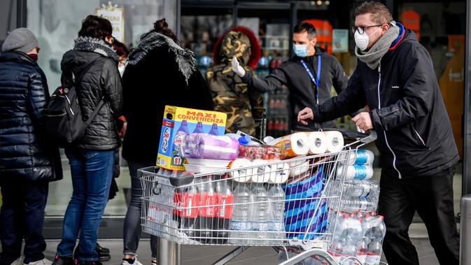 Orang-orang mengenakan masker antre di luar sebuah supermarket di Casalpusterlengo, Minggu (23/2/2020). Mereka memborong perlengkapan dan bahan-bahan kebutuhan pokok karena tak mau keluar rumah menyusul dua warga Italia yang meninggal karena Virus Corona COVID-19. (Claudio Furlan/Lapresse via AP)