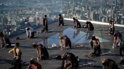 Praktisi yoga menghadiri kelas di Edge Observation Deck, Manhattan, New York, Amerika Serikat, Kamis (17/6/2021). Di tempat ini, para praktisi bisa berlatih yoga sambil menghadap cakrawala. (Ed JONES/AFP)