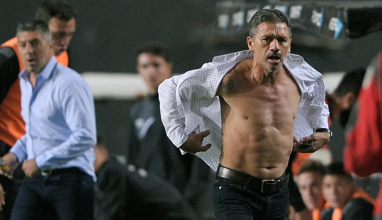 Pelatih Estudiantes, Nelson Vivas saat merobek kemejanya saat pertandingan melawan Boca Juniors di stadion Ciudad de La Plata, Argentina (6/5). Kejadian ini membuat Vivas dimirip-miripkan seperti superhero Hulk. (AFP Photo/Alejandro Pagni)