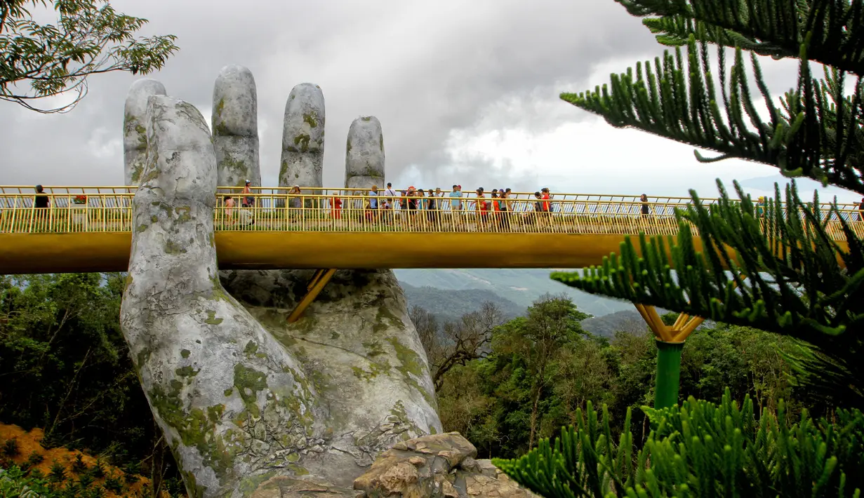 Pengunjung berjalan di sepanjang Golden Bridge di Perbukitan Ba Na dekat Danang, Vietnam, Selasa (31/7). Sesuai dengan namanya, jembatan ini dilapisi emas berkilau. (Linh PHAM/AFP)