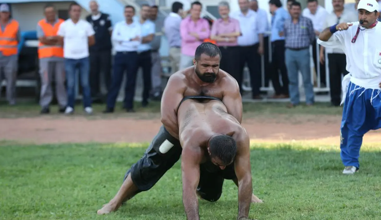 Pertandingan gulat oli ini di pimpin oleh seorang wasit. (AFP Photo/Adem Altan)