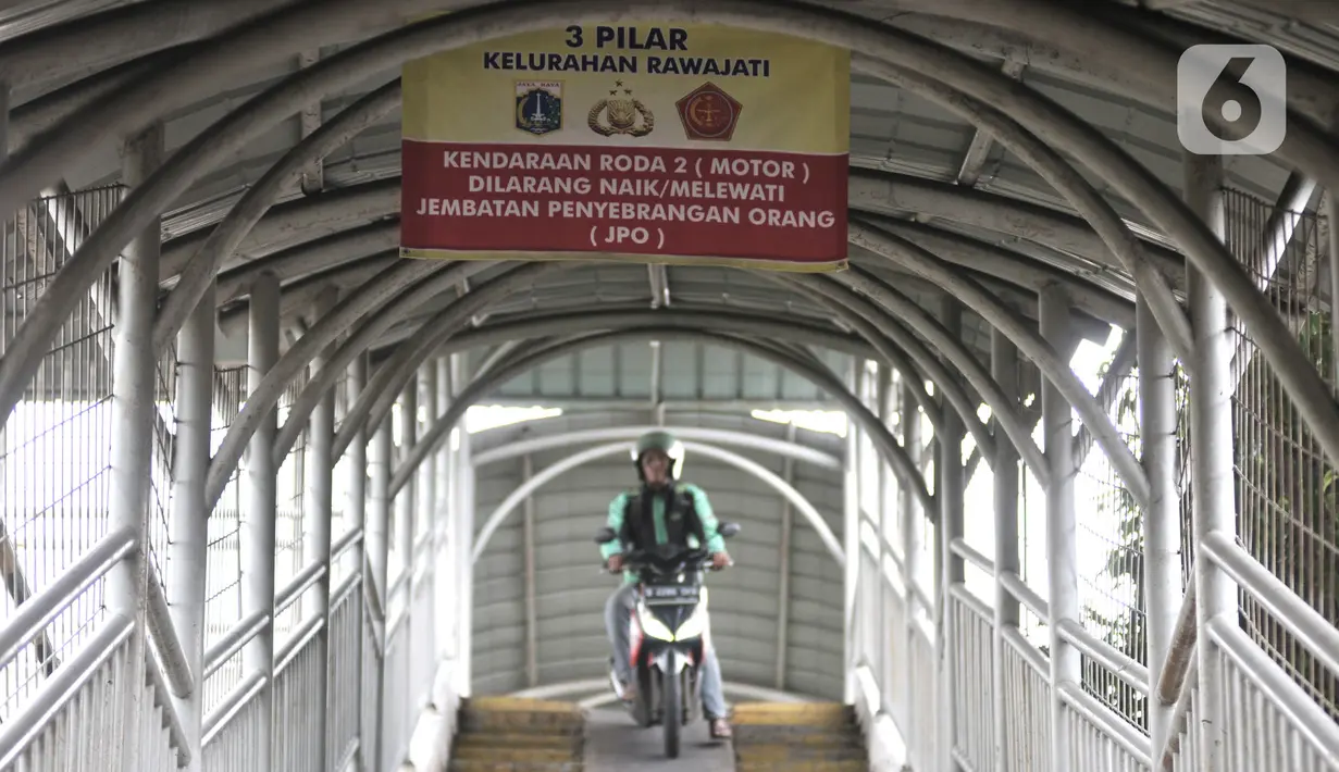 Pengendara sepeda motor melintasi rambu larangan saat melewati jembatan penyeberangan orang (JPO) Stasiun Pasar Minggu Baru, Jakarta, Selasa (10/3/2020). JPO tersebut kerap digunakan pengendara sepeda motor untuk menyeberang meski rambu larangan sudah dipasang. (merdeka.com/Iqbal Nugroho)