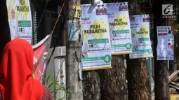 Pejalan kaki melintas dekat Alat Peraga Kampanye (APK) yang dipasang di pohon kawasan Ciater, Tangerang selatan, Senin (1/4). Pemasangan APK sejumlah caleg yang dipaku di pohon melanggar peratuan KPU Nomor 15 Tahun 2013 tentang tata cara pemasangan APK pemilihan umum. (merdeka.com/Arie Basuki)