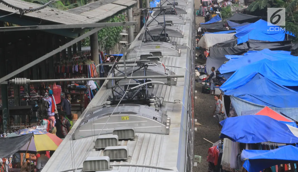 Suasana saat kereta commuter line melintas di rel KRL Nambo yang dipadati aktivitas jual beli pasar dadakan, Citeureup, Bogor (20/4). Meskipun berbahaya para pedagang tetap menjajakan dagangannya di tempat tersebut. (Merdeka.com/Arie Basuki)