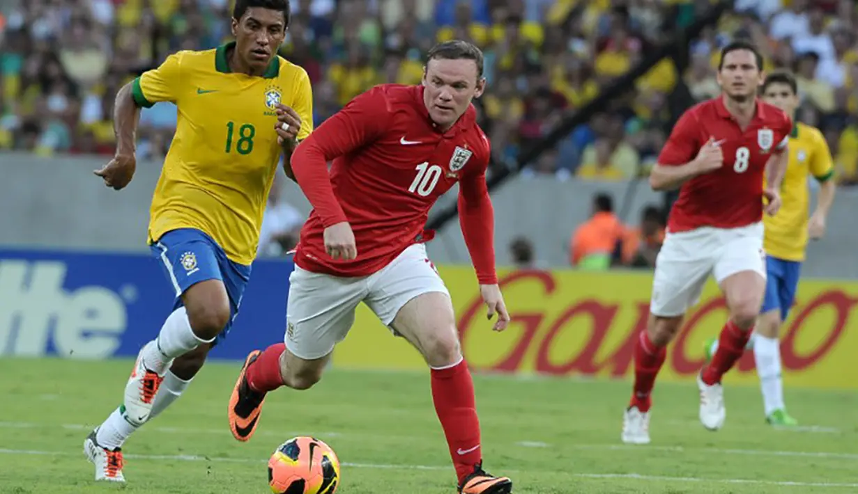 Wayne Rooney menggiring bola melewati pemain Brazil, Paulinho pada laga persahabatan di Stadion Maracana, Brazil, Minggu (2/6/2015). (AFP Photo/Yasuyoshi Chiba)