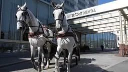 Pengemudi mengendarai kereta kuda di depan Hotel Intercontinental di distrik ke-3 di Wina, Austria pada 8 April 2020. Kereta yang disebut Fiaker yang biasanya mengangkut turis semenjak pandemi Corona beralih fungsi menjadi pengantar makanan untuk lanjut usia di daerah tersebut. (ALEX HALADA/AFP)