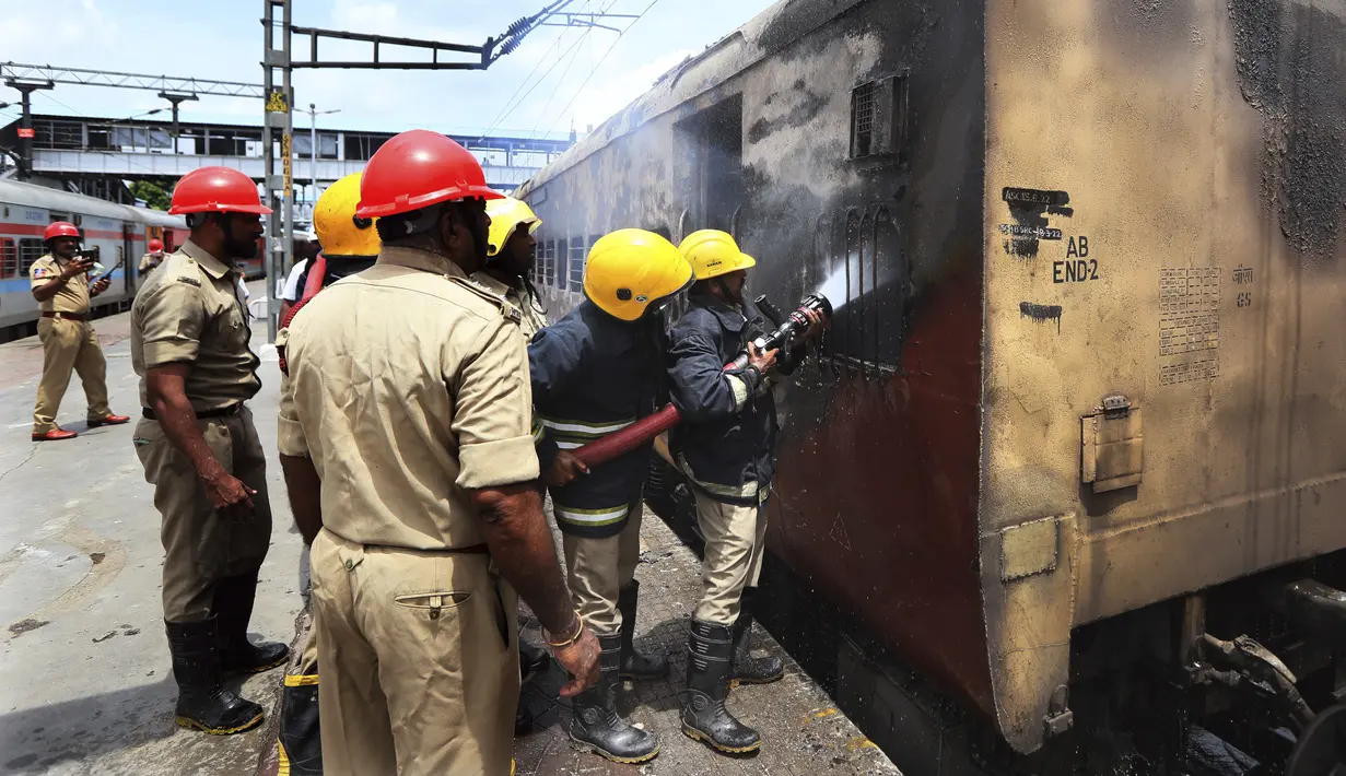 Petugas kereta api memadamkan api di gerbong kereta api di stasiun kereta api Secundrabad di Hyderabad, India, Jumat (17/6/2022). Hampir 500 pengunjuk rasa jauh melebihi jumlah polisi saat mereka mengamuk selama lebih dari satu jam di stasiun kereta api Secundrabad di India selatan. (AP Photo/Mahesh Kumar A)